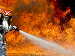 Imagem de 2 bombeiros combatendo um incêndio