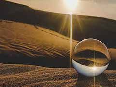 Fotografia de uma esfera transparente sobre a areia de uma praia